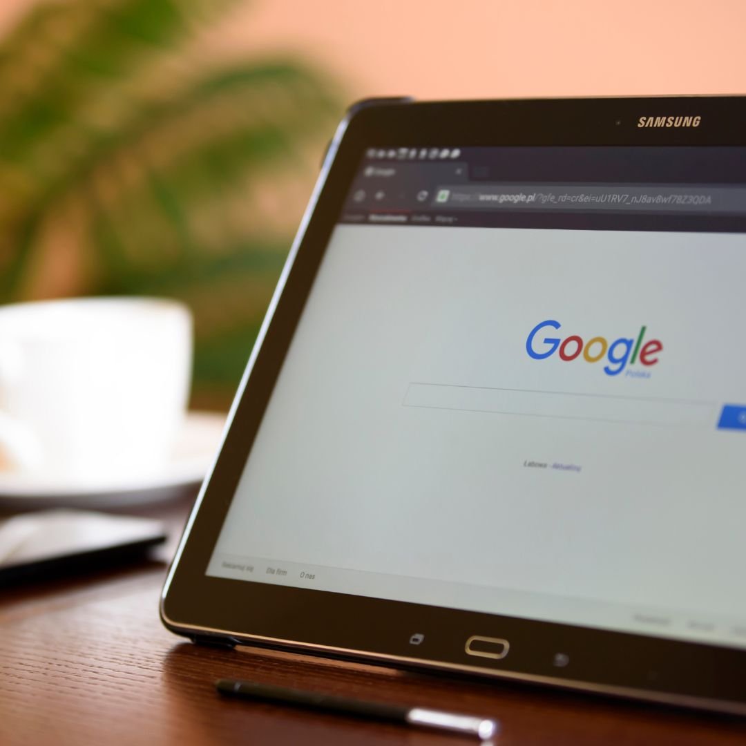 A tablet with Google search engine on the screen.  A white coffee cup is on a desk in the background.